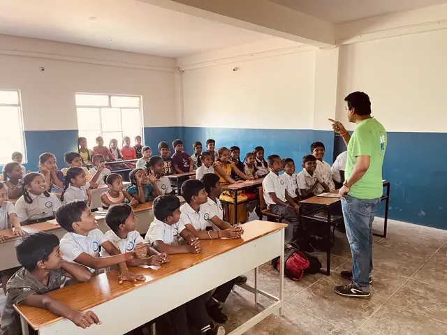 Full classroom of children at long benches, a teacher at the front, daylight flooding the window wall