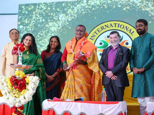 A row of guests and staff stand together on stage with bouquets in front of the school's crest