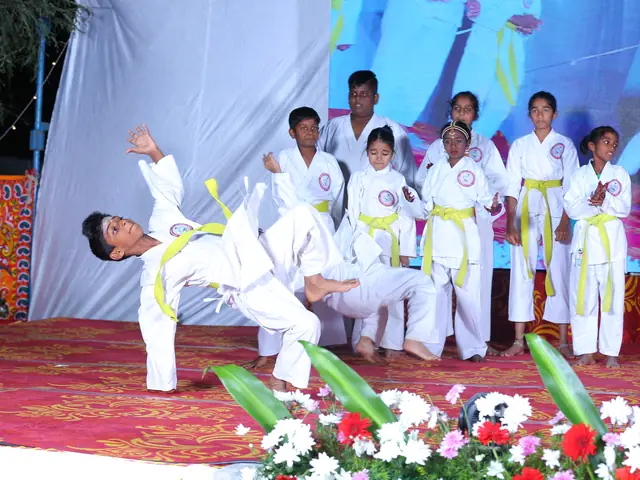 A boy in a white karate gi caught mid-air in a flying kick while his squad stands behind