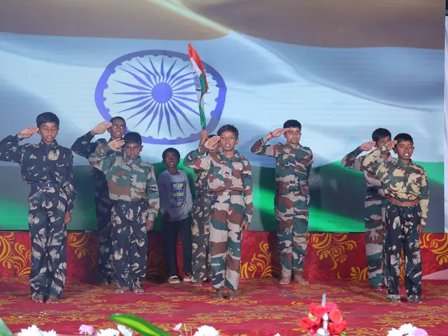 A line of children in fatigues stand at salute across the stage before a full-width projected tricolour