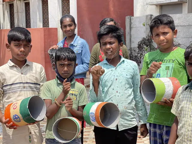 Five boys shoulder to shoulder holding brightly painted craft pots against a red wall