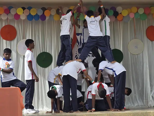 Boys in white shirts form a human pyramid on the stage, one at the top with arms raised