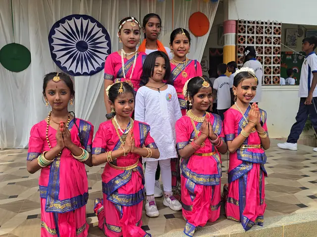Small girls in pink folk costumes standing with palms joined in namaste on the tiled courtyard