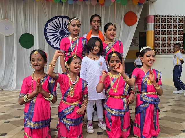 Girls in pink folk costumes strike a dance pose with one arm raised