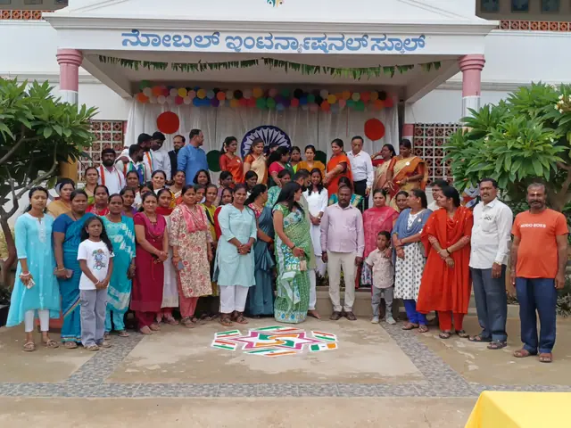 A large mixed group on the school forecourt with the Kannada-signed building and rangoli behind