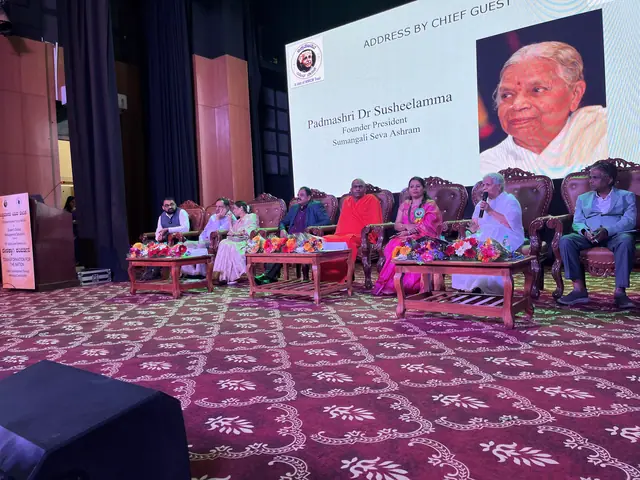 Wide auditorium view of the dais with seated panellists and a projection screen