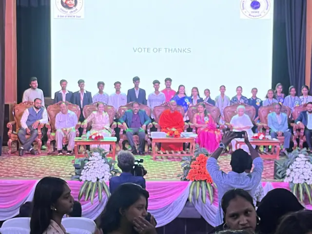 A large formal group on the auditorium stage, students behind seated dignitaries