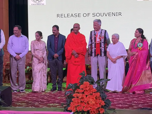 Guests including a saffron-robed swami stand across the stage during the souvenir release