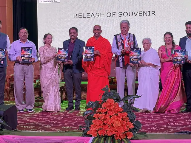 A dozen guests hold up copies of a souvenir book on the auditorium stage