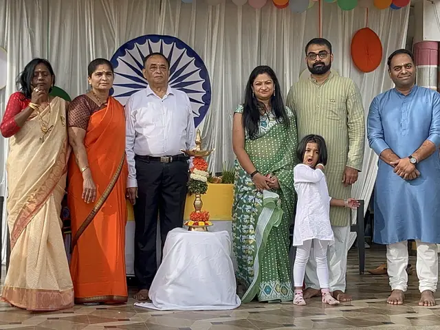 Six adults and two children posed in front of the white drape and Ashoka chakra roundel