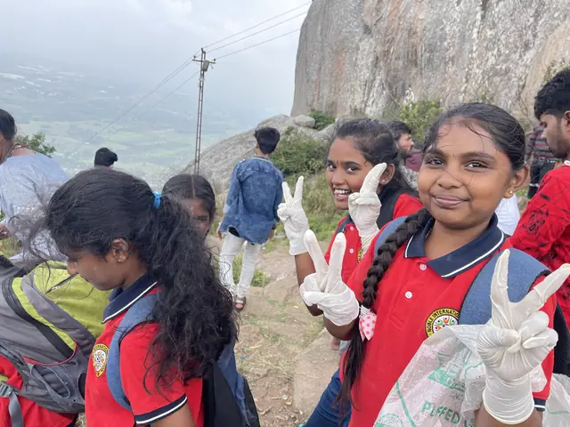 Two girls hold up gloved hands in peace signs during a hill clean-up