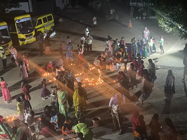 Families spread across the school steps at nightfall placing hundreds of lit oil lamps