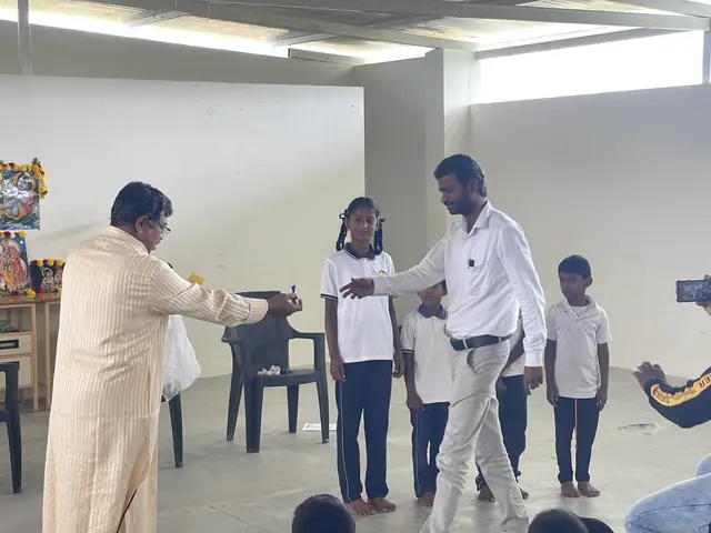 A man shaking hands with a schoolgirl at a prize-giving while a line of children waits