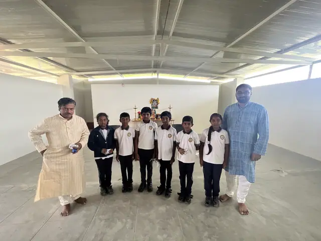 A row of six small boys standing shoulder to shoulder between two men in kurtas