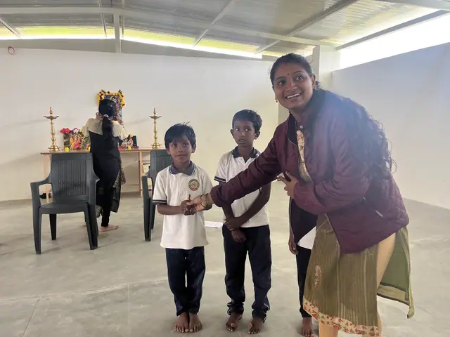 A woman leaning in with a broad smile towards two small boys holding their prizes
