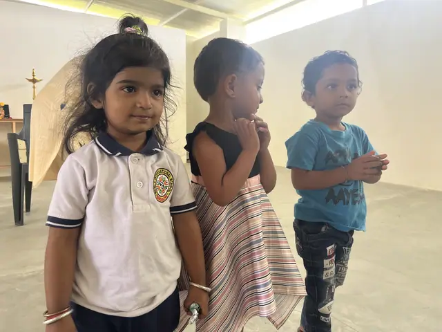 Three small children close to camera in the bright hall, soft daylight on their faces