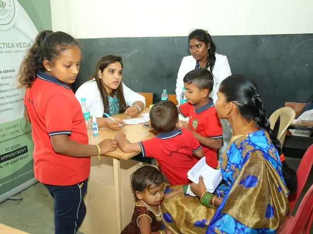 Two schoolgirls help a mother holding a toddler at a table, another small child at her knee
