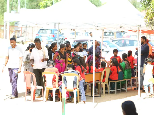 Wide view of the health camp on the school grounds with white canopy tents and rows of seated people