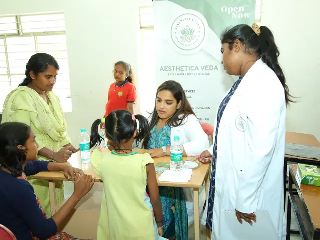 Two small children sit at a table with their mothers while a woman in a white coat stands nearby