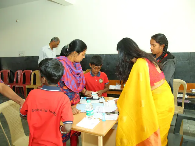 A woman in a saffron sari stands over a table where children sit with forms and water bottles