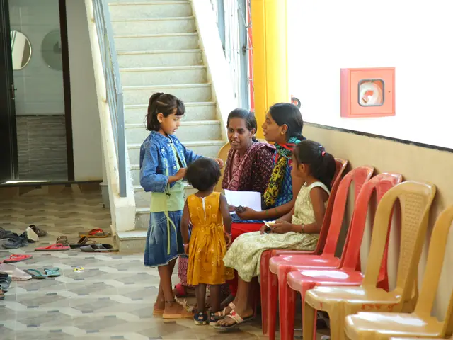 Interior of the school entrance hall with a concrete staircase and yellow walls, women and children seated