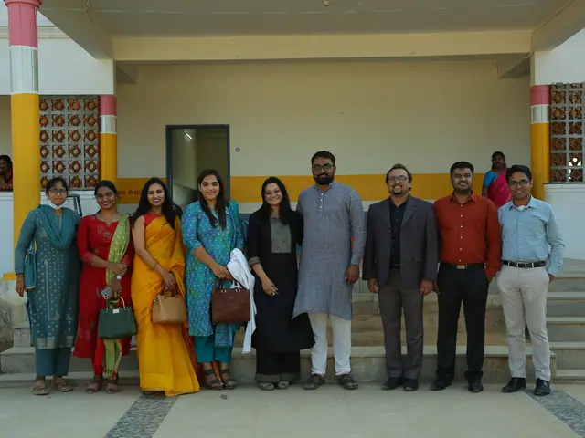 Group portrait of about ten staff under the school's pillared portico with pink and yellow columns