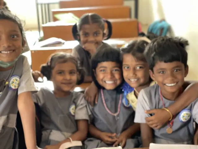 Tight group of six young children pressed cheek to cheek, all grinning broadly into the lens