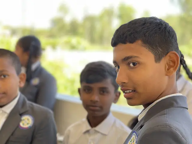 An older boy turns to look straight at the camera with two younger boys behind him