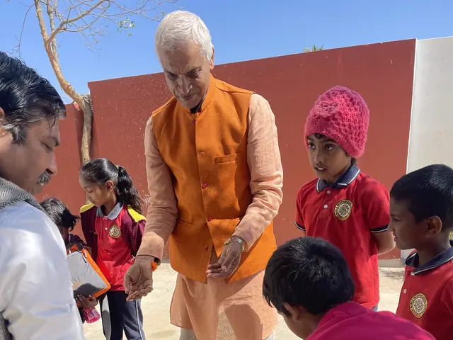A white-haired man in an orange kurta plants a sapling while schoolchildren crowd in to help
